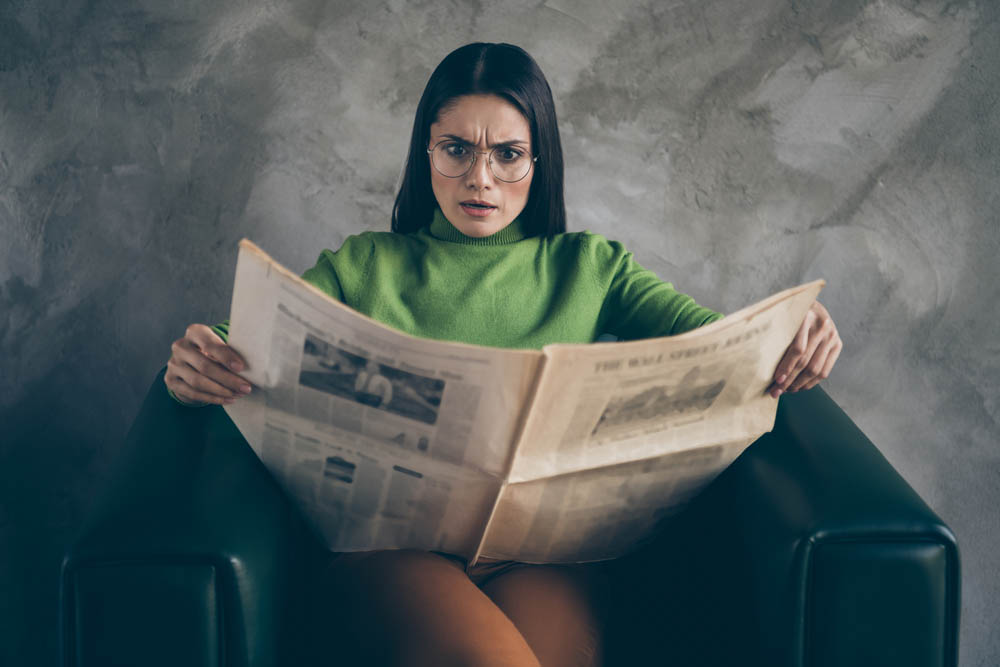 Photo of outraged shocked woman in stupor reading fake terrible headlines, news about her corporation sitting in armchair isolated grey color wall concrete background