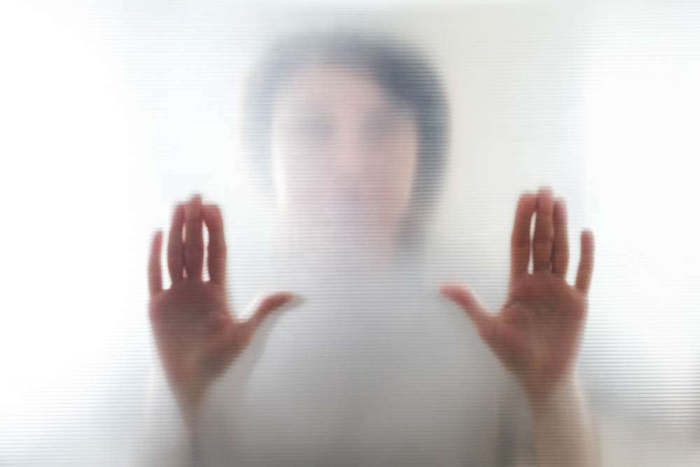 Diffused silhouette of female hands through frosted glass